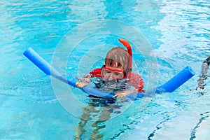 Little boy learns swimming alone with pool noodle