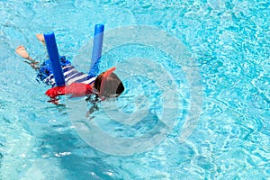 Little boy learns swimming alone with pool noodle