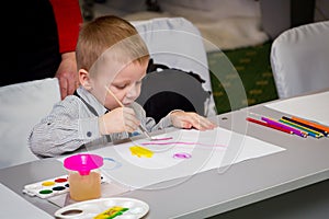 A little boy learns to paint with a brush