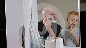 A little boy learns to shave with his dad in the bathroom.