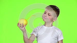 Little boy lemon with a straw and drinks juice from it. Green screen. Slow motion