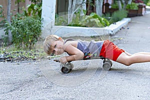 A little boy licking on a skateboard near the house on the road.