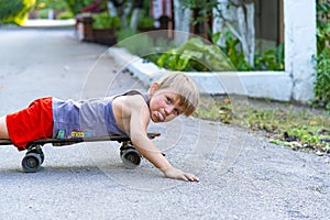 A little boy licking on a skateboard near the house on the road.