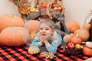A little boy lies on the floor near pumpkins and autumn fruits. Autumn Festival