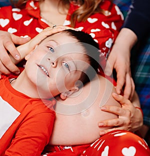 a little boy lies on the stomach of a pregnant mother. happy family