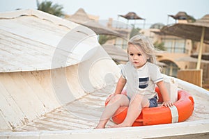 Pequeno chico línea de vida sobre el Playa. sentarse en anillo sobre el soleado. un nino cabello tener divertido externo. verano 