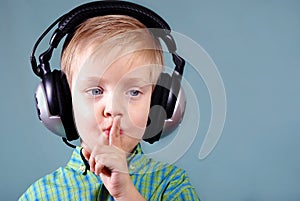 Little boy listening music on headphones. sign quieter