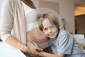 Little boy listening to mom pregnant belly