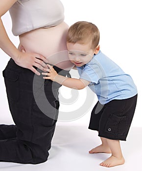 Pequeno chico escuchando sobre el mamás barriga 