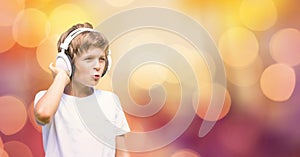 Little boy listening to music on headphones over blur background