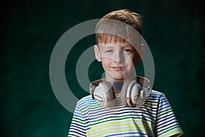 Little boy listens to his favorite music in modern wireless headphones, in the studio