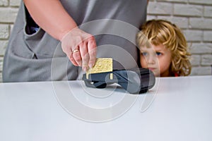 Little boy with long hair looking at the payment process through the terminal