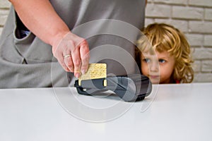 Little boy with long hair looking at the payment process through the terminal