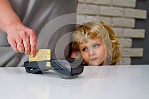 Little boy with long hair looking at the payment process through the terminal