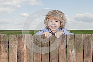 Little boy looking from above a fence,