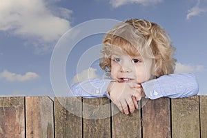 Little boy looking from above a fence,