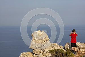 Little boy looking at binoculars on blue sea in Rhodes Greece.