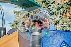 Little boy looking through binoculars on a slide at the Playground.