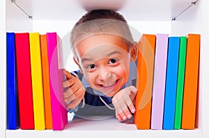 Little boy looking through book shelf