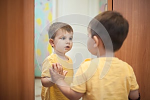 Malý chlapec pozerá na sám najbližšie zrkadlo 