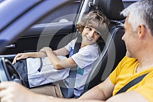 Little boy looking at his mature father in the car