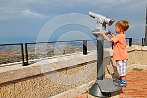 little boy looking through sightseeing binoculars on San Marino.