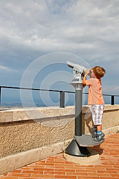 little boy looking through sightseeing binoculars on San Marino.