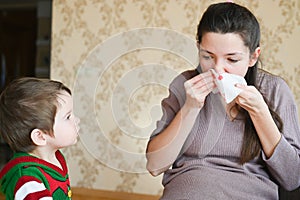 The little boy looks at a sick pregnant mother. Pregnant young woman with nosebleed. Severe pregnancy concept