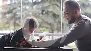 Little boy looks at smartclock on father's hand