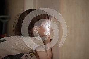 The little boy looks in the window of the door. A child spying on his parents from behind the closed bedroom door