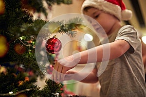 A little boy decorating a Christmas tree with his mother at home. Together, New Year, family, celebration