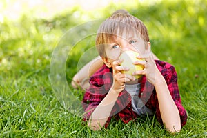 Little boy lying on grass with apple