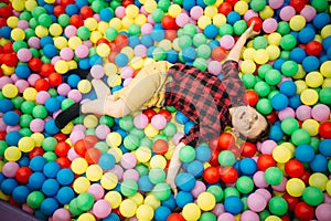 Little boy lying in a pile of colorful balloons