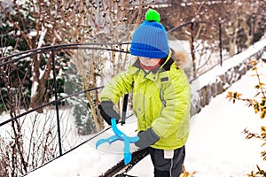 Little boy makes snowballs with snowball maker. Happy child playing with snow. Cold winter weather. Winter activities for kids.