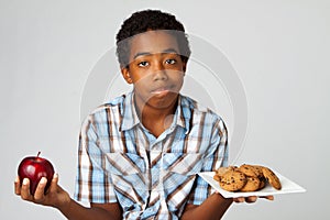 Little boy making decisions of eating healthy verses unhealthy.