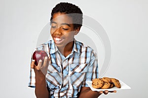 Little boy making decisions of eating healthy verses unhealthy.