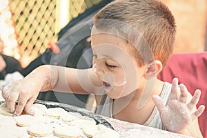 Little boy making dumplings at table