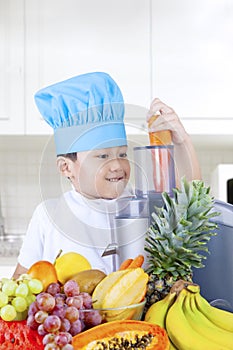 Little boy making fresh fruits juice