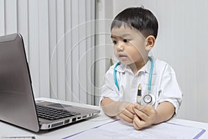 Little boy in medic uniform holding a pen on desk. Childhood dream and Careers in children\'s dreams concept
