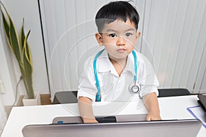 Little boy in medic uniform using a laptop on desk, Careers in children`s dreams concept