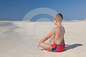 The little boy meditating on the beach