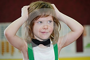 little boy medium plan. The boy is dressed in a bow tie. the child has long hair and an emotional facial expression. The