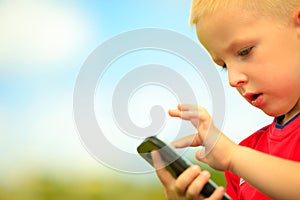 Little boy with mobile phone outdoor. Technology generation.