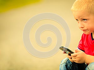Little boy with mobile phone outdoor. Technology generation.