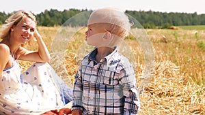 Little boy with mom resting in field on hay