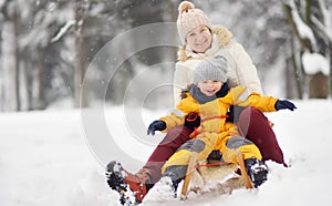 Little boy and mother/grandmother/nanny sliding in the Park during a snowfall