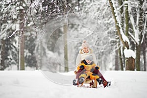 Little boy and mother/grandmother/nanny sliding in the Park during a snowfall