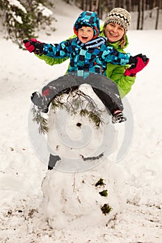 Little boy and mother posing on big snowman