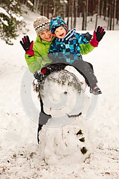 Little boy and mother posing on big snowman