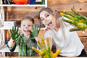 Little boy and mother showing hands painted in colorful paints